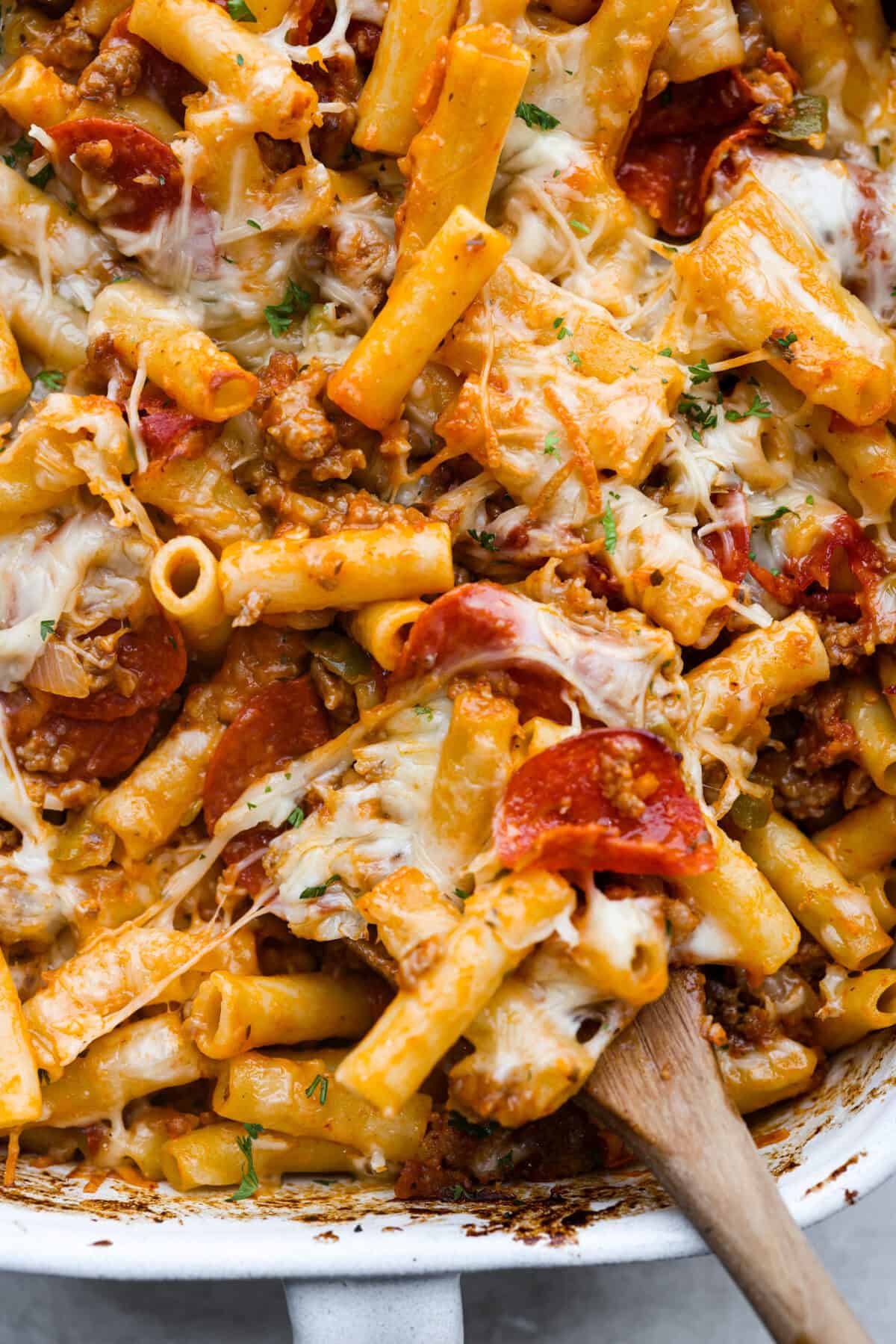 This cheesy baked ziti is baked to perfection with al dente noodles, spicy pepperoni, flavorful sausage, and smothered in melty cheese. It comes together quickly and easily and can be made ahead of time for busy weeknights! Close up shot of cheesy baked ziti.