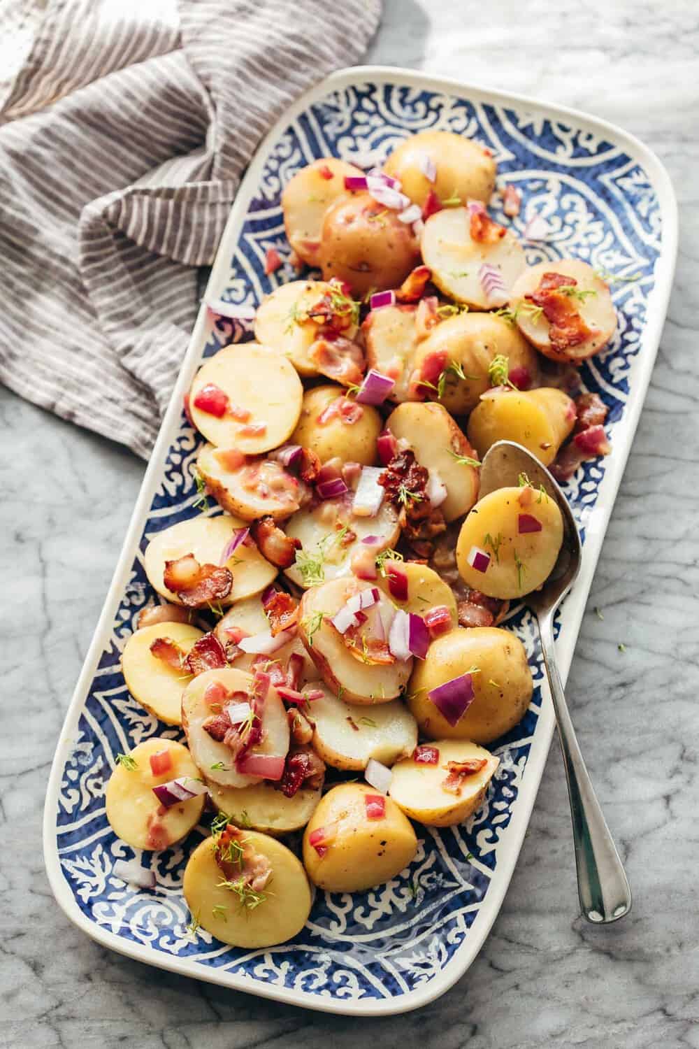 German Potato Salad is a great alternative to the traditional American Potato Salad and has loads of flavour from a tangy, bacony dressing! German Potato Salad served on a platter