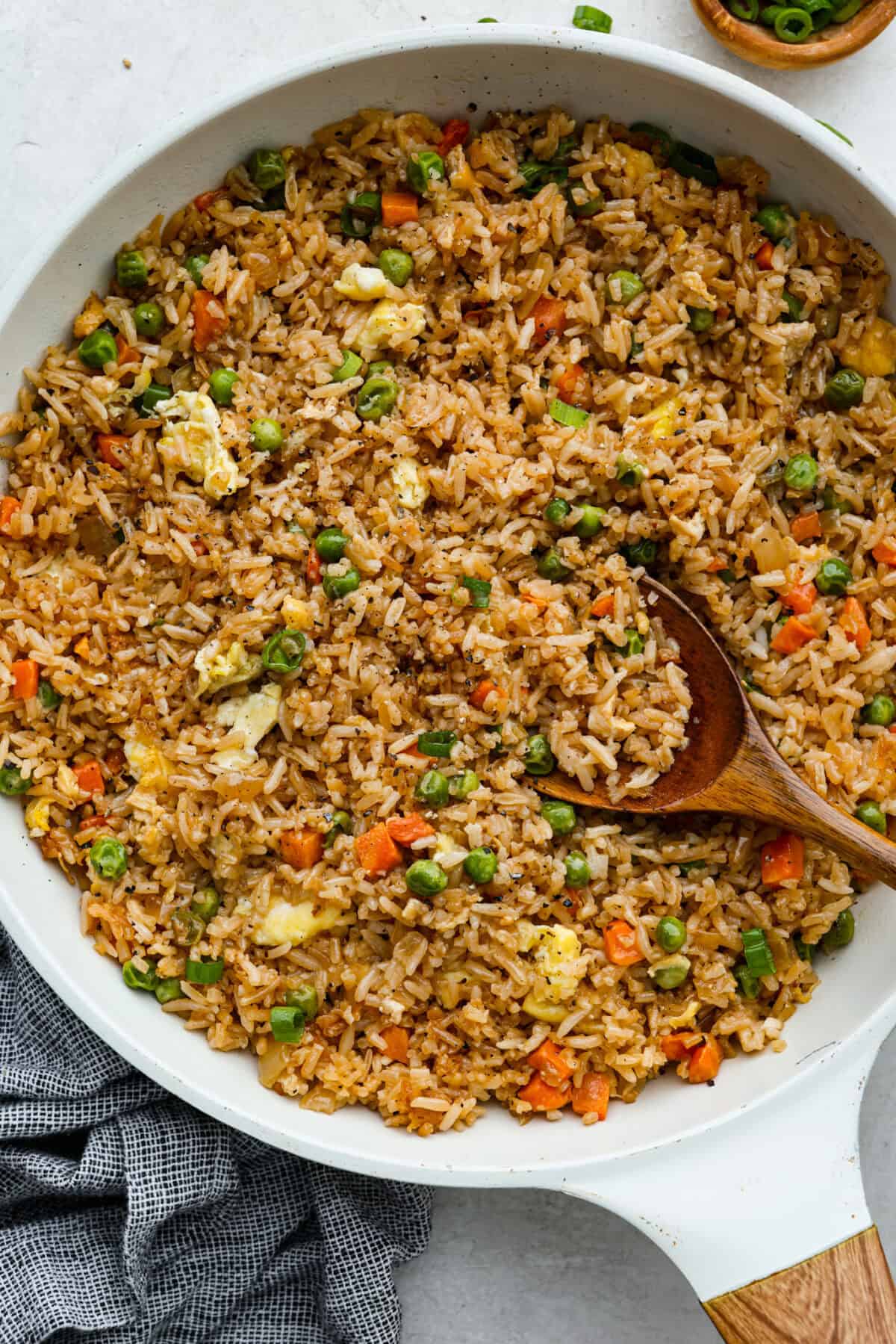 Overhead shot of easy fried rice in a skillet with a wooden spoon. 