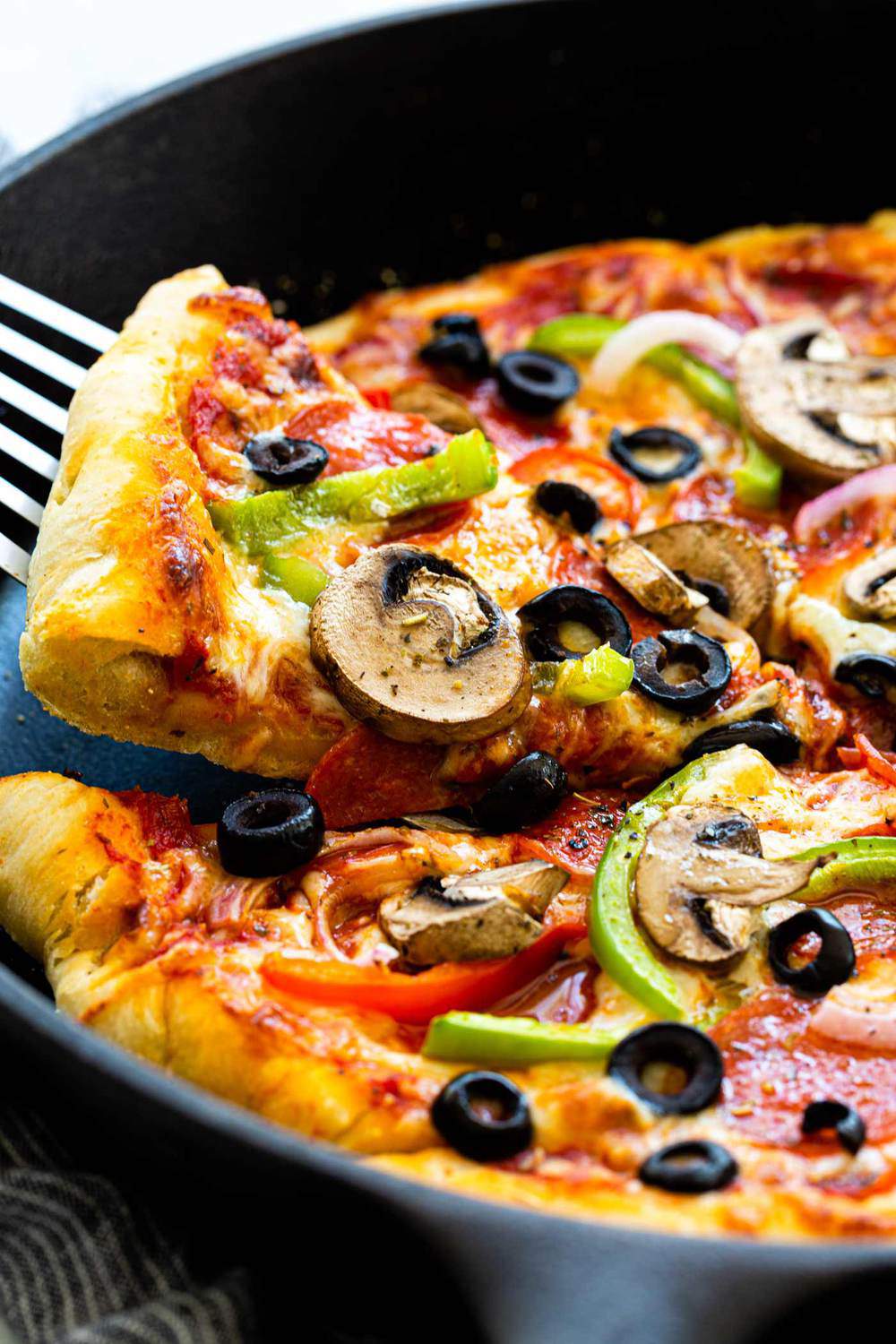 This Skillet Pizza is made supreme style, topped with a colorful mix of pepperoni, bell peppers, onions, mushrooms, and olives. The pizza dough is cooked in a hot cast-iron skillet to ensure a crispy crust. Grab a hot slice of cheesy homemade pie, it will disappear fast! Skillet Pizza