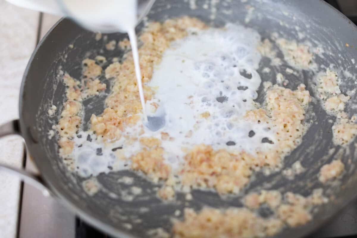Creamed Spinach is a classic and delicious side dish! It is loaded with fresh spinach and has the creamiest garlic parmesan sauce. Serve it alongside any meal! Fourth photo of the milk adding to the saucepan.