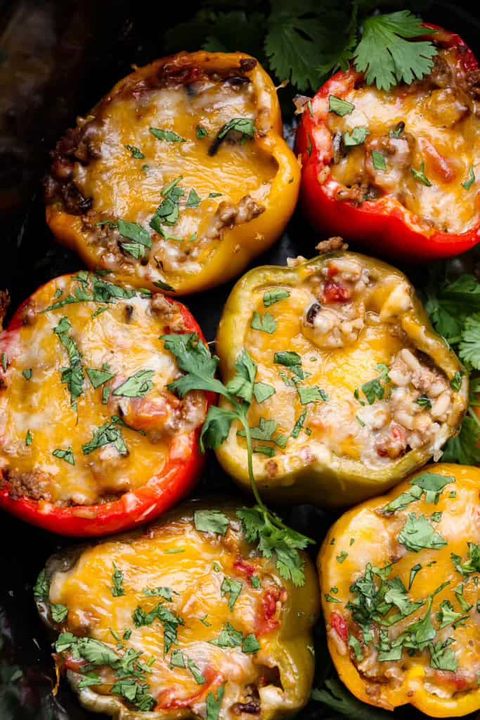 Slow cooker stuffed bell peppers are packed with ground beef, wild rice, diced tomatoes, soft black beans, and melty cheese. They cook to perfection in the slow cooker and make a healthy, delicious dinner your whole family will love! Close up shot of slow cooker stuffed bell peppers.