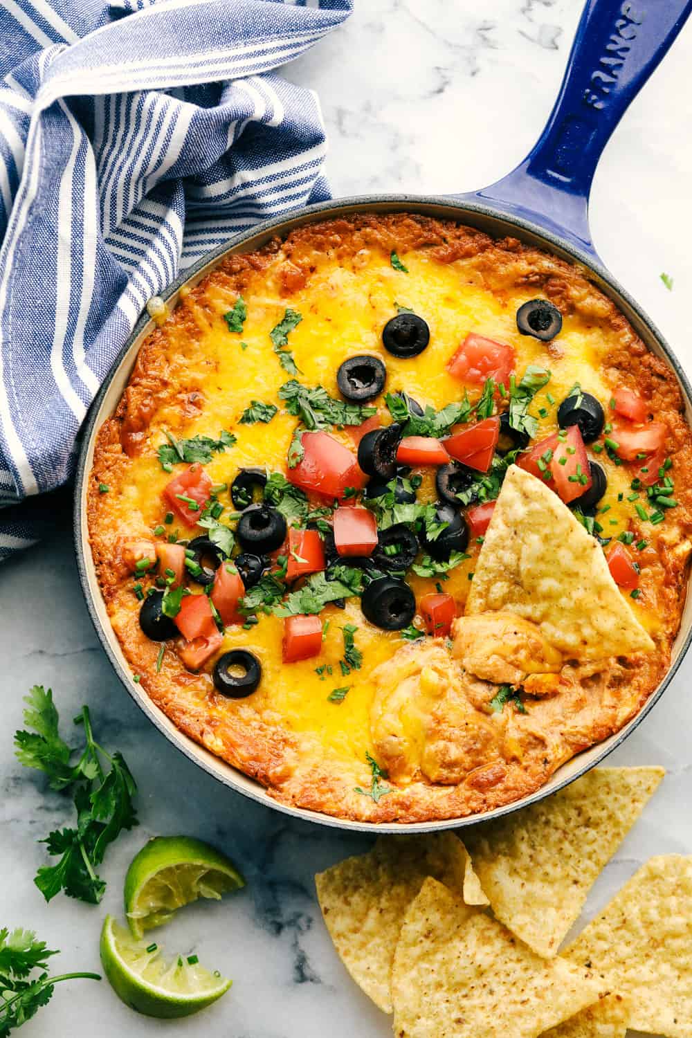 Bring out the chips and start dipping because this is the most addicting bean dip you will ever have! It's creamy, cheesy, and loaded with tasty Mexican-inspired flavors. Garnish with toppings, and take this to your next gathering! Bean dip in a blue cast iron pan with chips.