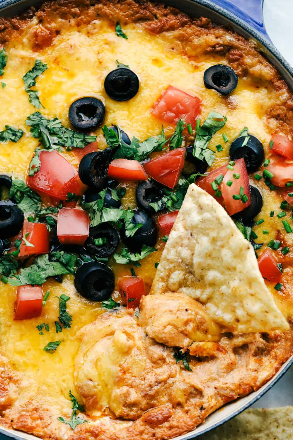Bring out the chips and start dipping because this is the most addicting bean dip you will ever have! It's creamy, cheesy, and loaded with tasty Mexican-inspired flavors. Garnish with toppings, and take this to your next gathering! Bean dip cooked with a chip in the middle of it.