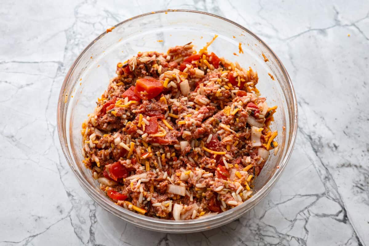 Slow cooker stuffed bell peppers are packed with ground beef, wild rice, diced tomatoes, soft black beans, and melty cheese. They cook to perfection in the slow cooker and make a healthy, delicious dinner your whole family will love! Overhead shot of meat, cheese, diced tomatoes, onion, rice, seasonings and cheese mixture.