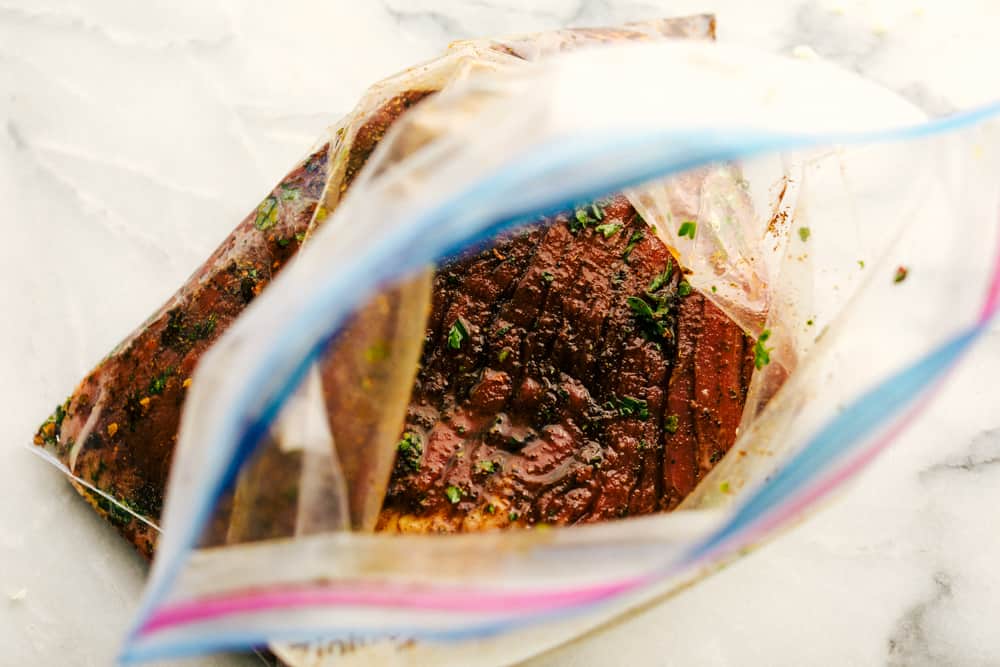 Amazing Steak Fajitas have tender marinated, juicy steak with colorful bell peppers wrapped in a soft shell tortilla topped with all your favorites. A complete dinner in 45 minutes! steak marinating in a ziplock bag
