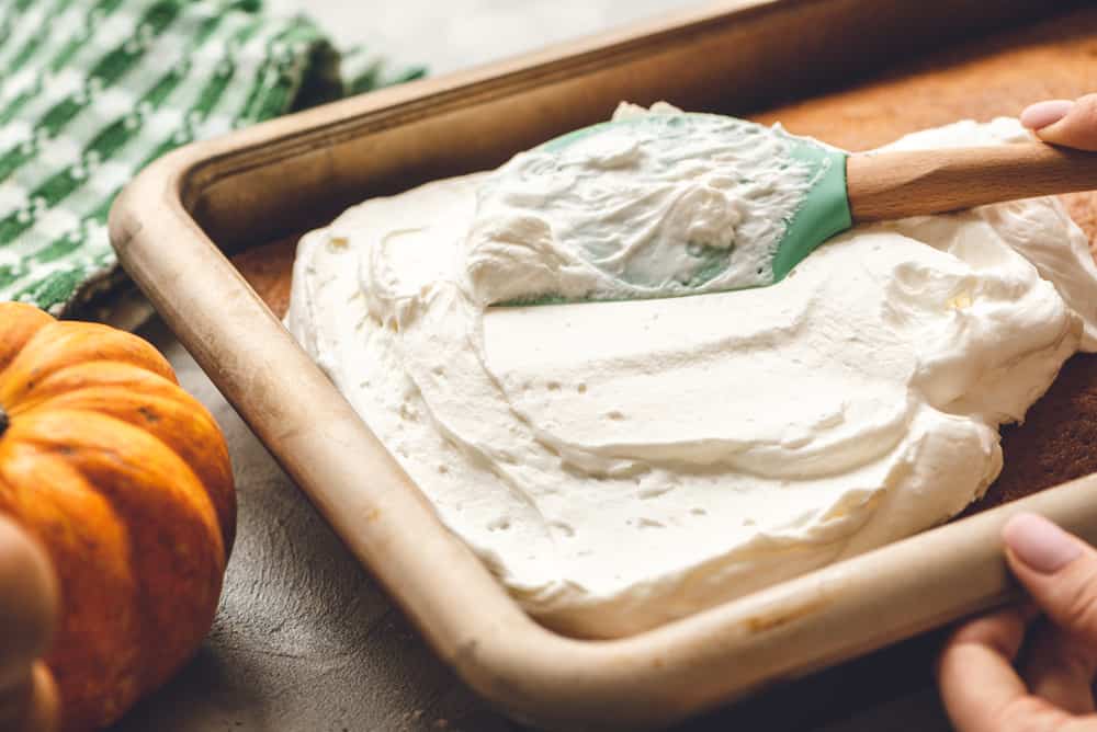 This Pumpkin Cake is the most amazing pumpkin cake you will ever make! ย Perfectly spiced and moist and topped with the most epic cream cheese whipping cream frosting! Pumpkin cake with whipping cream in a bowl