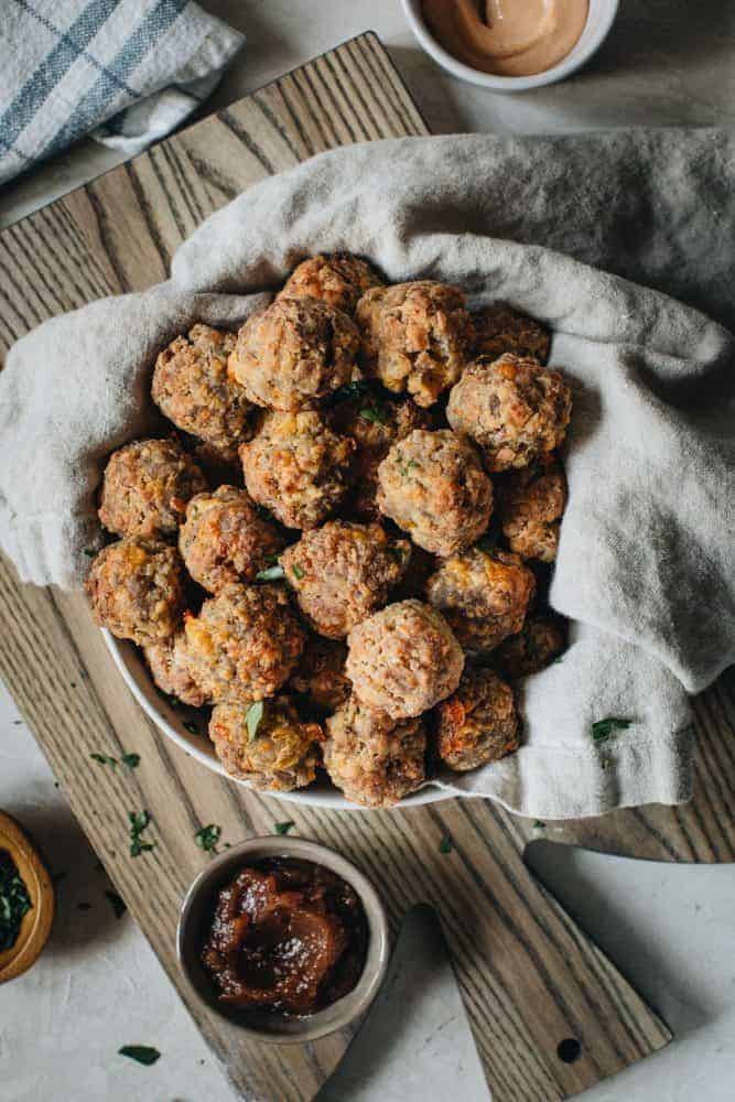Perfect party appetizers make the holidays sweeter and full of savory memories. These Easy Sausage Balls are a southern serving staple with simple ingredients or sausage, cheddar cheese, Bisquick, and olive oil. Easy Sausage Balls