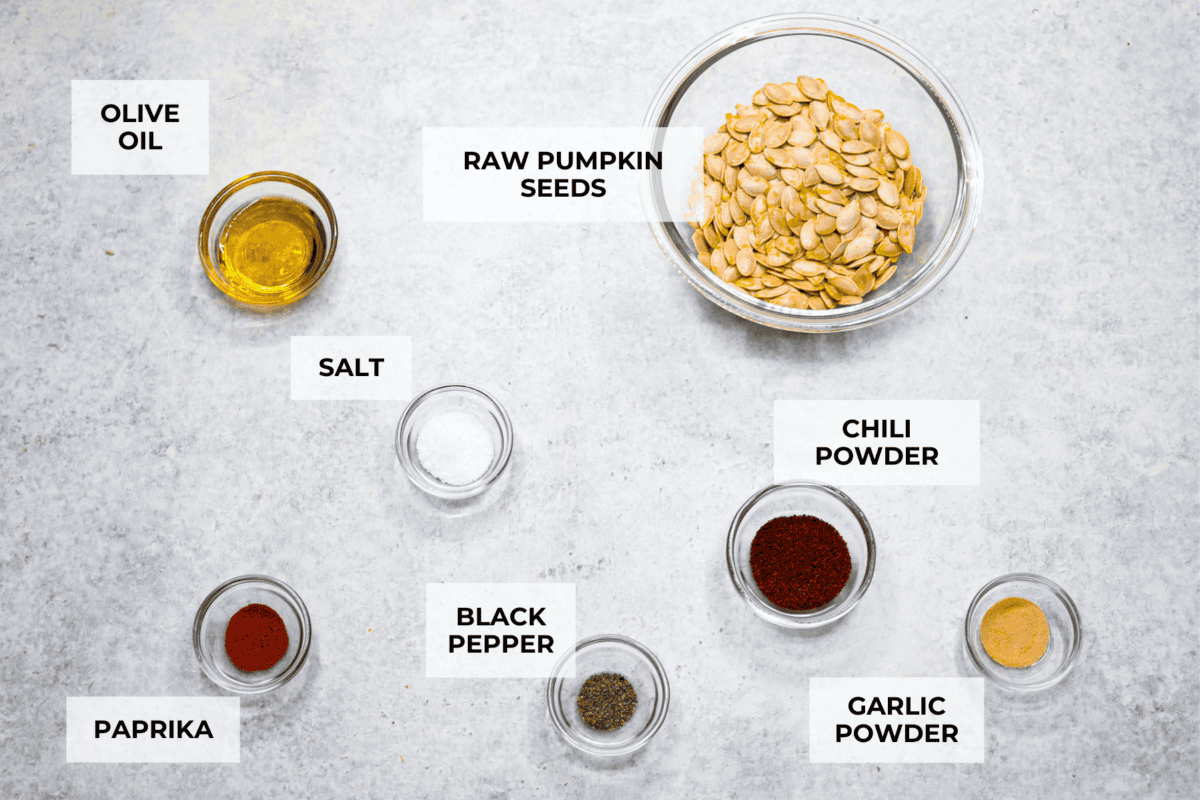 Crazy Good Roasted Pumpkin Seeds are a healthy and delicious snack you can enjoy while carving pumpkins this Halloween season. They are packed with essential vitamins and antioxidants that help you sleep better, boost your immune system, and promote heart health. Overhead shot of labeled ingredients.