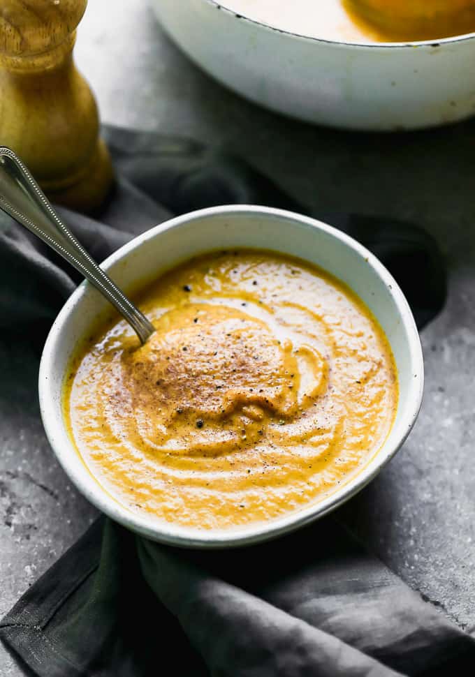 This Creamy Pumpkin Soup is packed with pumpkin flavor, a touch of sweetness, and velvety smooth. It's the perfect cozy fall soup, and it only takes 30 minutes to throw together! creamy pumpkin soup in a bowl