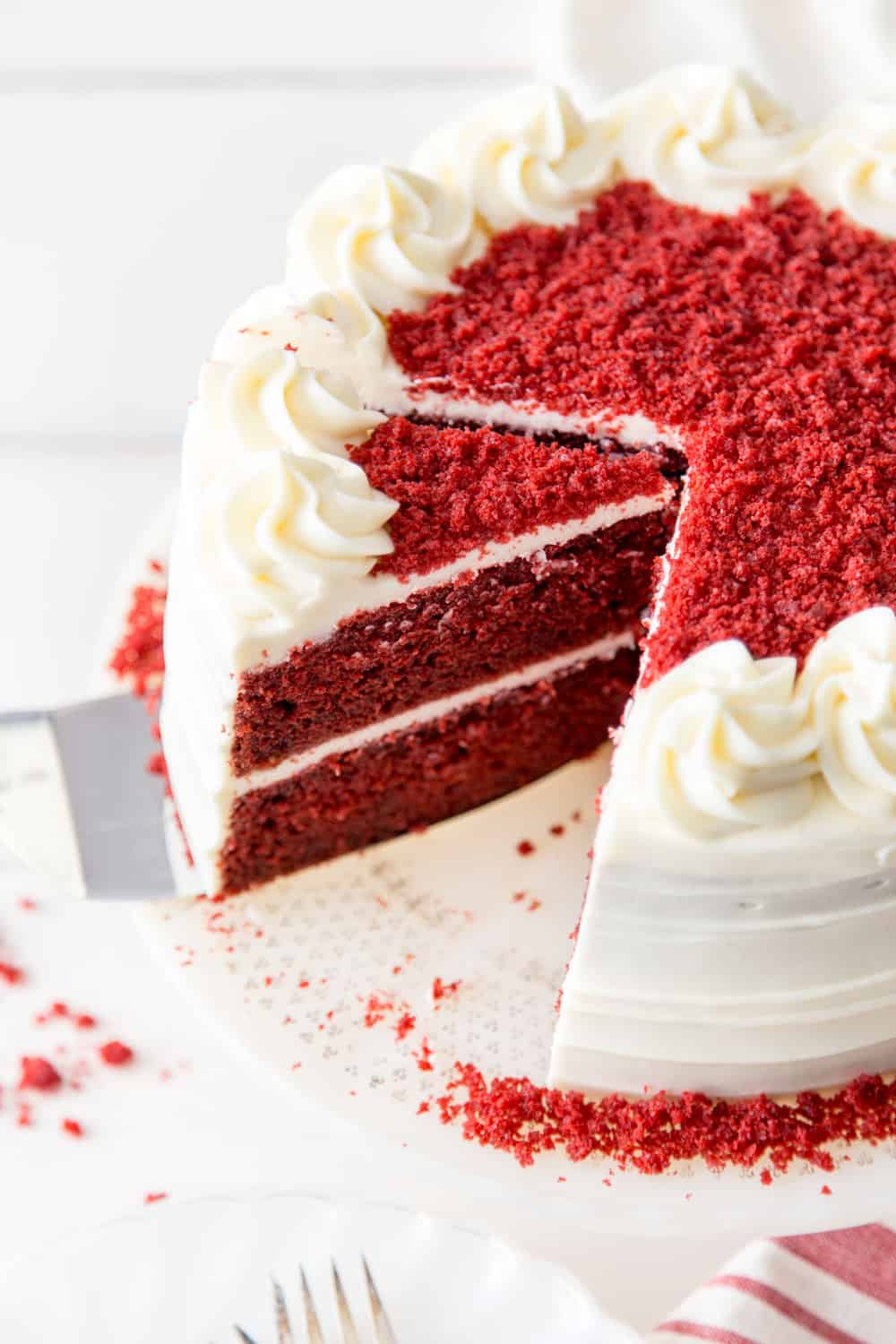 Red Velvet Cake Recipe is a classic must-have in your dessert arsenal. The super moist and slightly chocolaty cake, covered in a tangy cream cheese frosting, is the perfect way to end a great meal. Red velvet cake on a cake stand