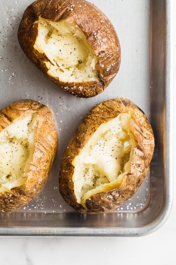 This Baked Potato Recipe is easy to make with just Russet potatoes and seasonings. Top it any way you like for the perfect side dish at any meal! baked potatoes overhead