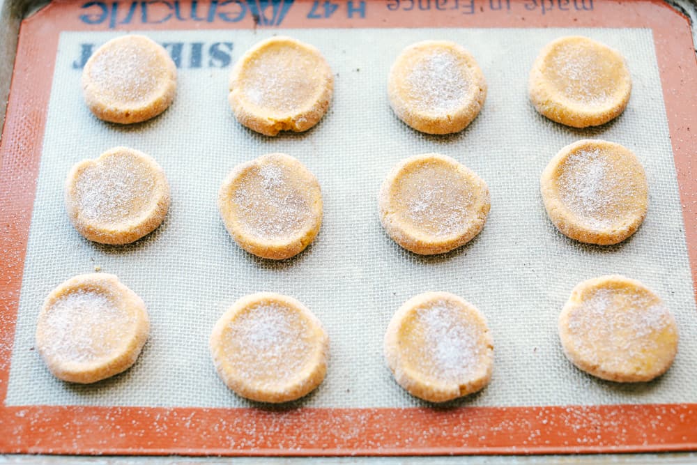 Soft and Puffy Pumpkin Snickerdoodles are made with real pumpkin, fall seasonal spices mixed together and rolled with pumpkin pie spice and aย touch of sugar to add that extra sweetness and fallย flavor! This are a MUST make this fall season! pumpkin snickerdoodle dough pressed down getting ready to bake.