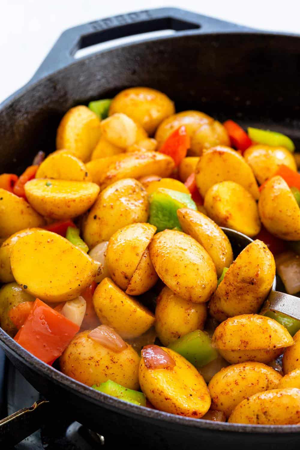 Skillet Potatoes are an easy side dish to make in one pan! The potatoes areย sautรฉedย with peppers and onions, then steamed until tender for flavorful spuds with each bite. cooking potatoes in a skillet