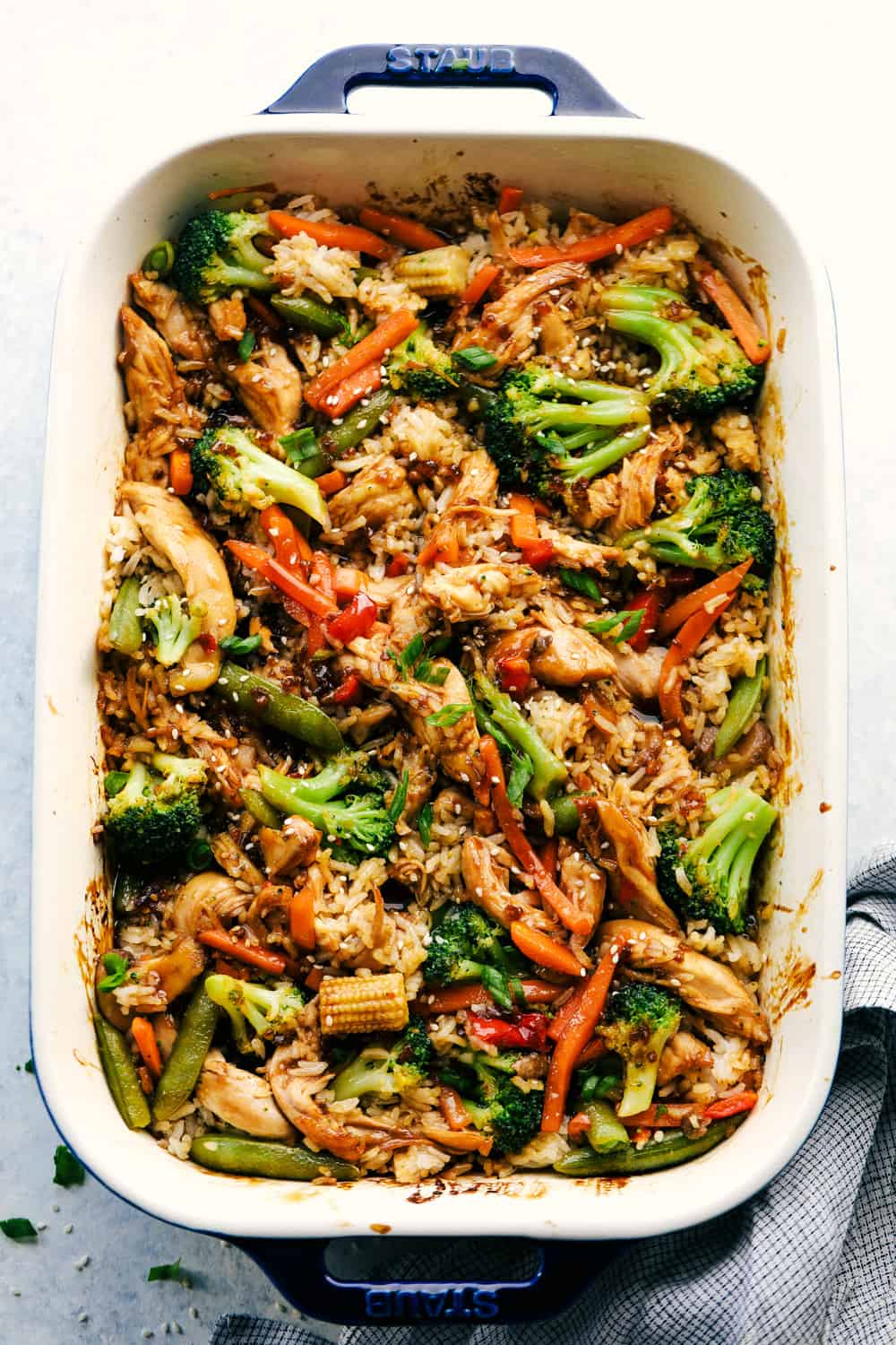 Easy Teriyaki Chicken Casserole isย a simple casserole made with homemade teriyaki sauce, vegetable stir fry and rice that's all baked to perfection. A savory dish that everyone loves!ย Chicken teriyaki casserole in a blue and white baking dish.