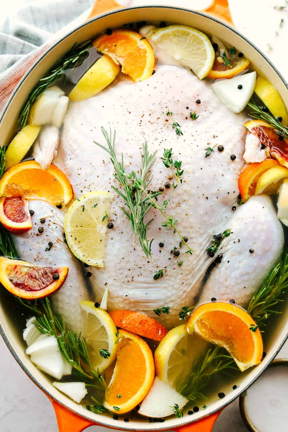 Turkey Brine creates aย tender, moist and juicy turkey withย sweet citrusy flavoring and a hint of spice all submerged in a water bath for your turkey to soak from the inside-out. Make your turkey irresistible this holiday season! Turkey in a pot being submerged by water and other seasonings for a brine.
