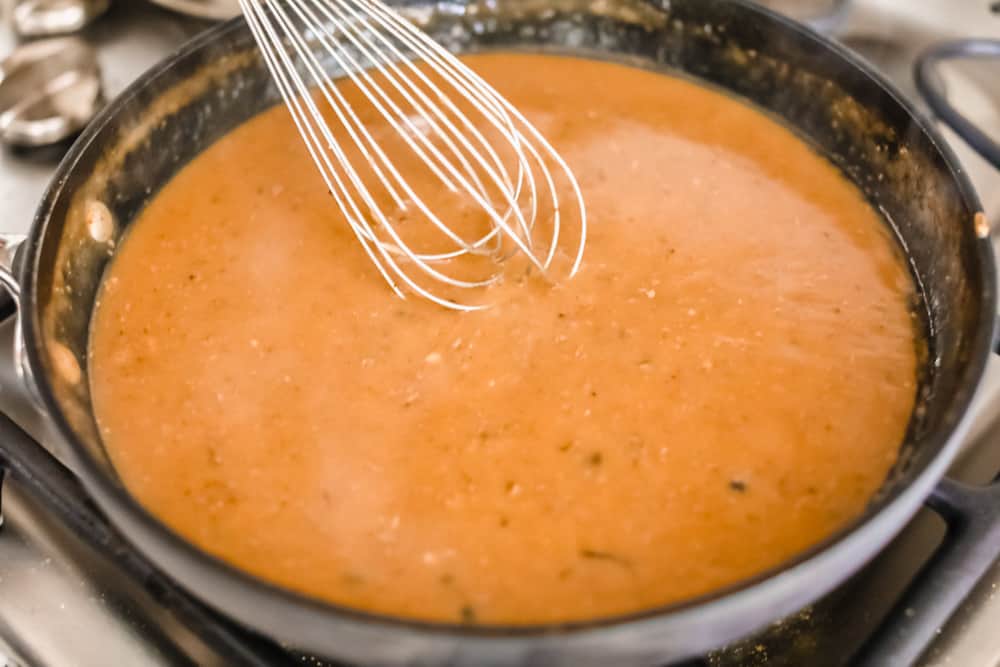 Look no further! This roasted turkey recipe is the absolute juiciest, fool-proof turkey recipe you will ever need. You'll have the confidence to make a perfect turkey every time. This deliciously seasoned turkey will be the star of your Thanksgiving meal! Turkey gravy whisking in a pan.