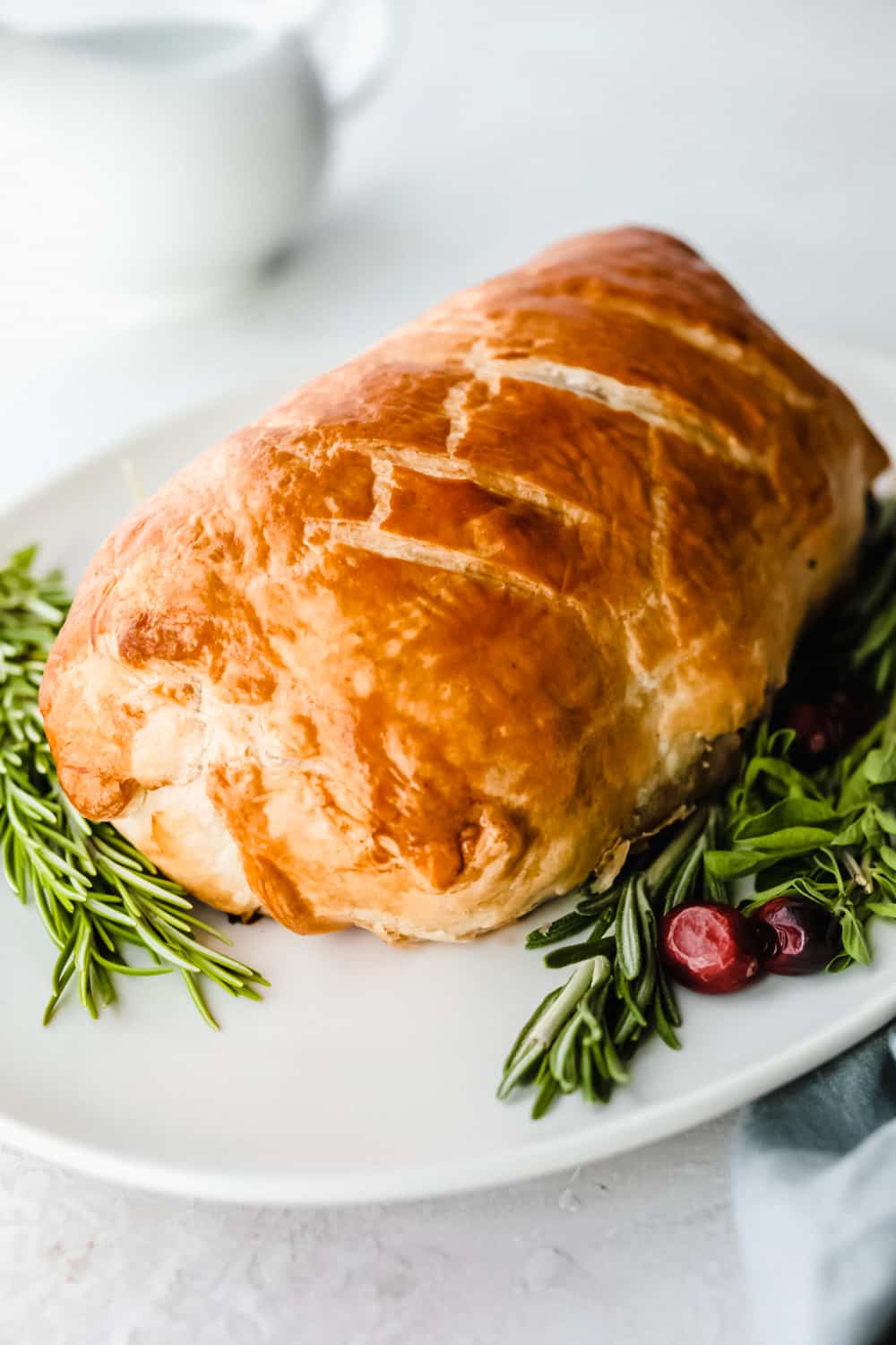 Best Ever Beef Wellington Recipe is a decadent tender and juicy beef tenderloin with a layer of mustard, mushroom sauce and prosciutto wrapped in a soft, buttery pastry that is cooked until golden brown. A holiday favorite! Beef Wellington baked on a plate