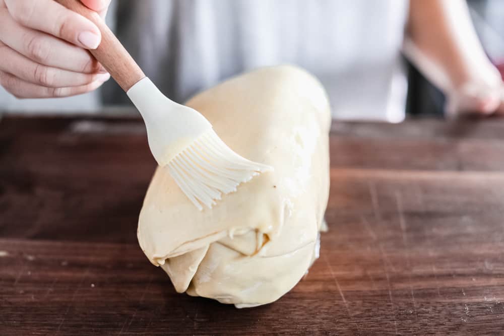 Best Ever Beef Wellington Recipe is a decadent tender and juicy beef tenderloin with a layer of mustard, mushroom sauce and prosciutto wrapped in a soft, buttery pastry that is cooked until golden brown. A holiday favorite! Beef layered with a puff pastry and getting butter brushed overtop.