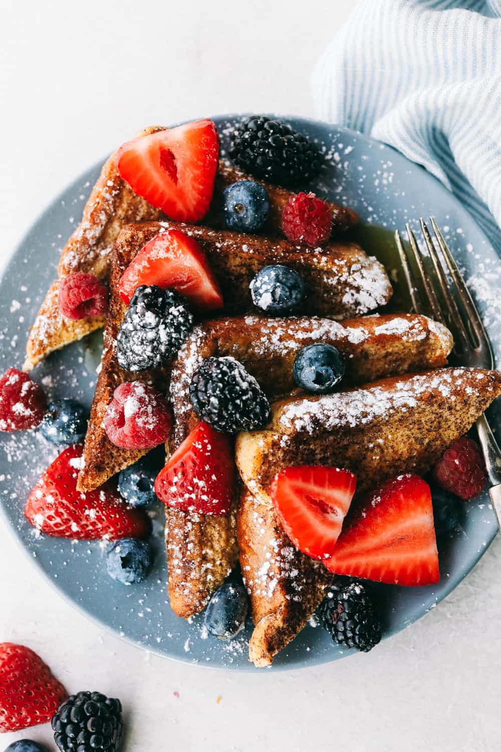 French Toastย is a sliced thick, chunky bread dipped in aย creamy egg, milkย and cinnamon mixture with a secret ingredient that will take thisย French toast over the top! A little slice of heaven on your plate!ย sliced French toast with berries on a plate