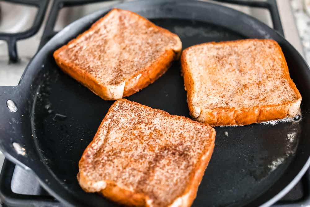 French Toastย is a sliced thick, chunky bread dipped in aย creamy egg, milkย and cinnamon mixture with a secret ingredient that will take thisย French toast over the top! A little slice of heaven on your plate!ย cooking French toast in a skillet on the stove top.