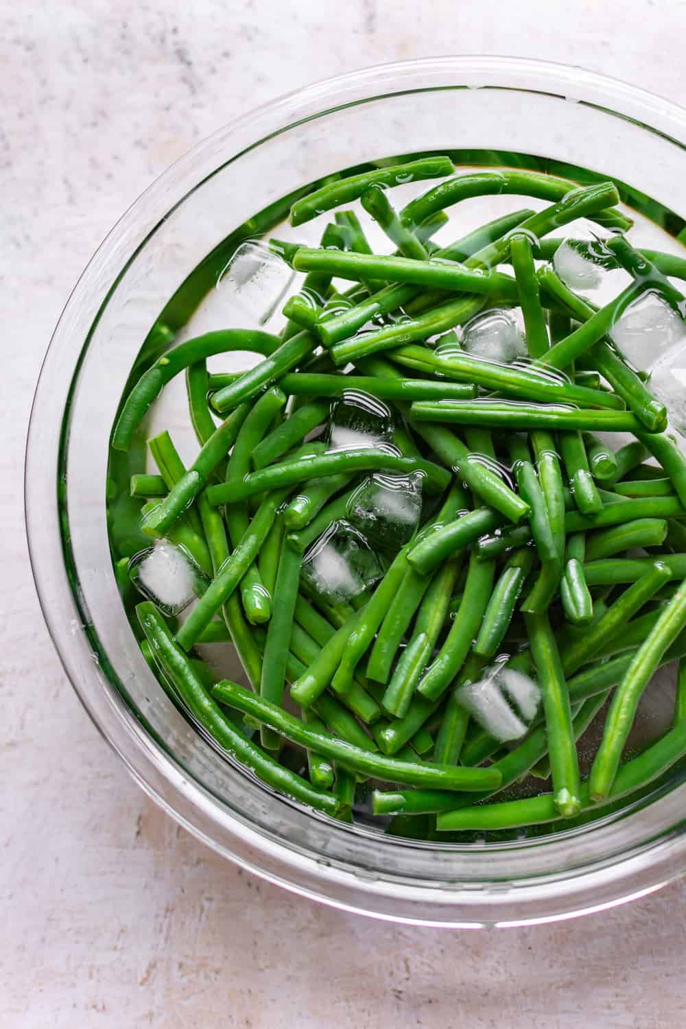 Garlic Butter String Beans (green beans) are the perfect easy side dish! Everyone will love these delectable tender-crisp string beans. A delicious healthier addition to your table.ย Garlic Butter String Beans in a bowl with water