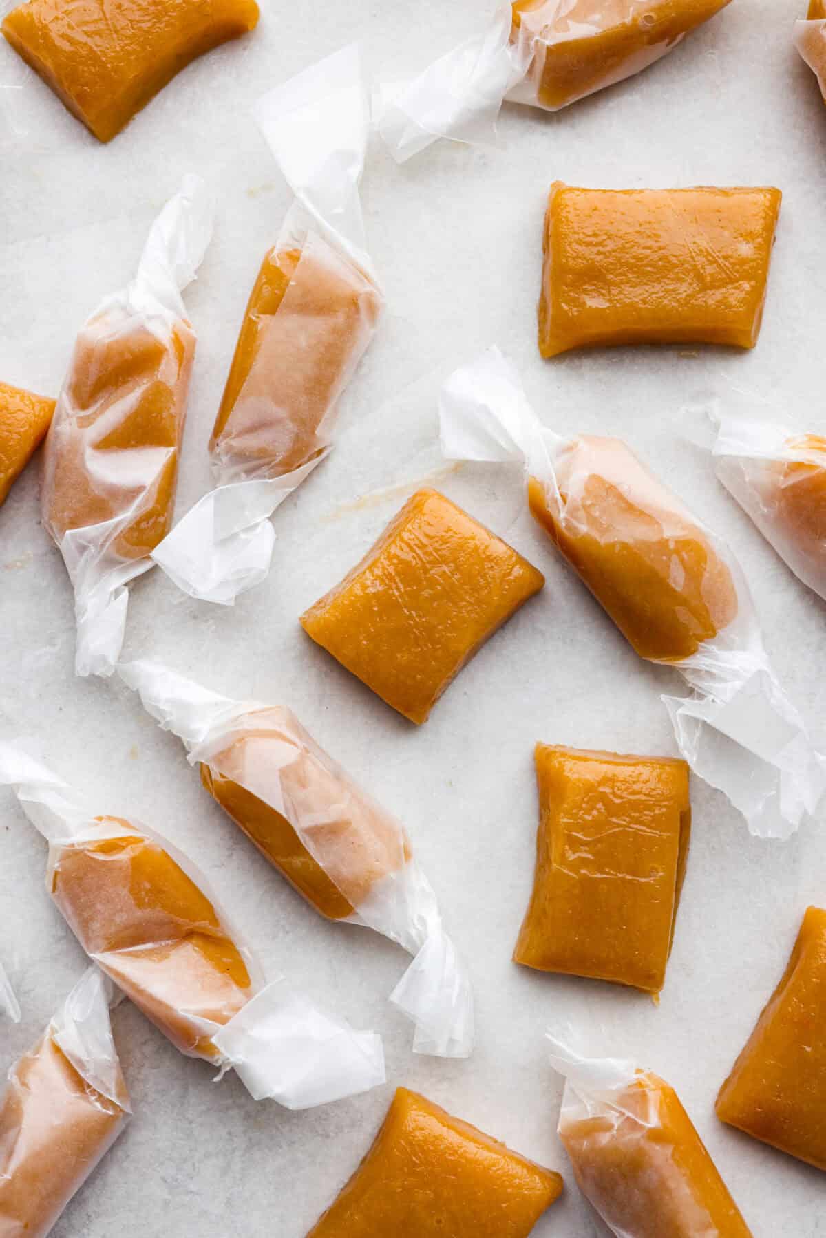 Homemade Caramels are perfectly buttery soft with just the right amount of sweet. They are easy to make and are the perfect neighbor gift for the holiday season. Overhead shot of wrapped and unwrapped caramels.