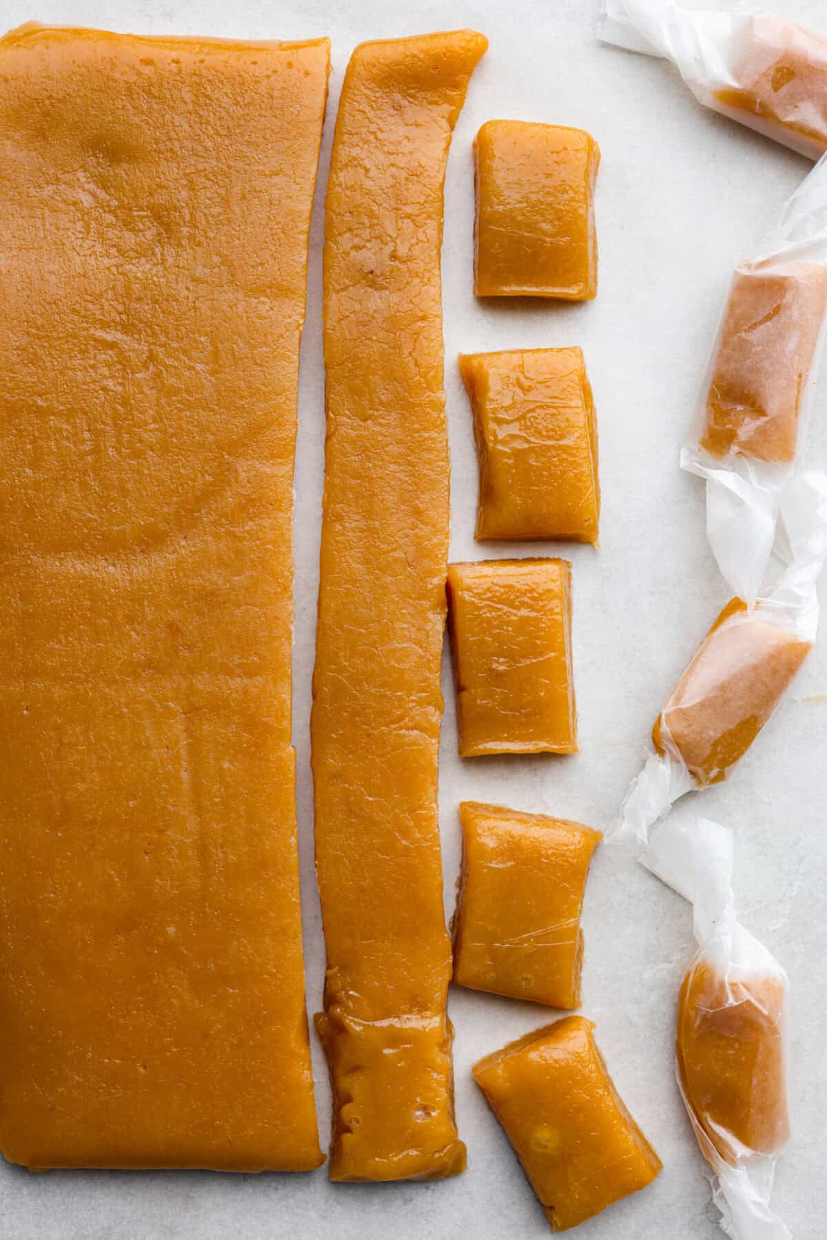 Homemade Caramels are perfectly buttery soft with just the right amount of sweet. They are easy to make and are the perfect neighbor gift for the holiday season. Close up shot of the caramels cut up, and wrapped in different stages.