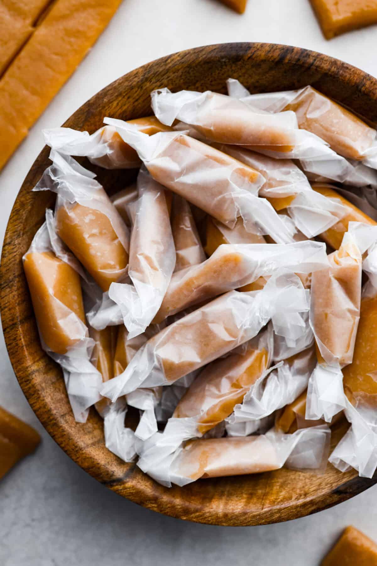 Homemade Caramels are perfectly buttery soft with just the right amount of sweet. They are easy to make and are the perfect neighbor gift for the holiday season. Overhead shot of a bowl of wrapped homemade caramels.