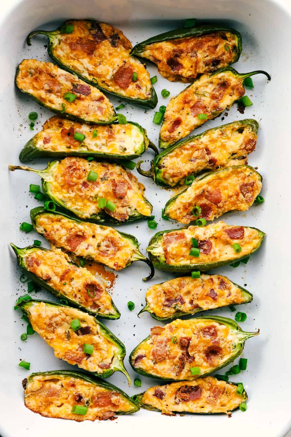 These jalapeรฑoย poppersย are filled with a cream cheese mixture, topped with crumbled bacon pieces, and then baked to perfection. You won't be able to stop at one!ย Jalapeรฑo poppers being baked.