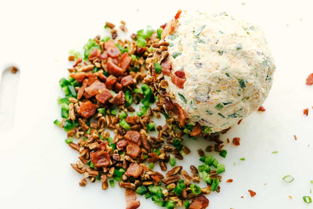 This jalapeno bacon cheese ball is perfectly creamy, rolled in crunchy bacon, and topped off with green onions and salty pecans. It's the perfect holiday appetizer and filled with SO much flavor! Rolling the cheese ball in the bacon, pecans, peppers, and onions.