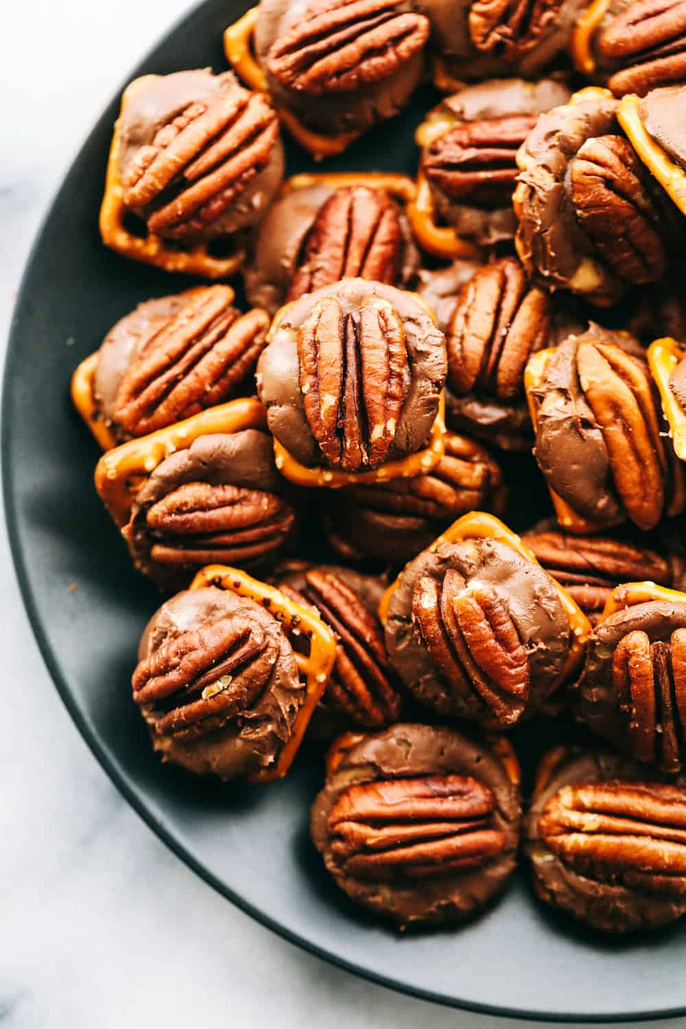 This Rolo Pretzel Turtle Recipe has a hard, salty pretzel layered with a caramel hidden inside a chocolate for a creamy inside topped with a crisp pecan. This salty and sweet treat is perfect for the holidays this season! rolo pretzel turtles on a plate