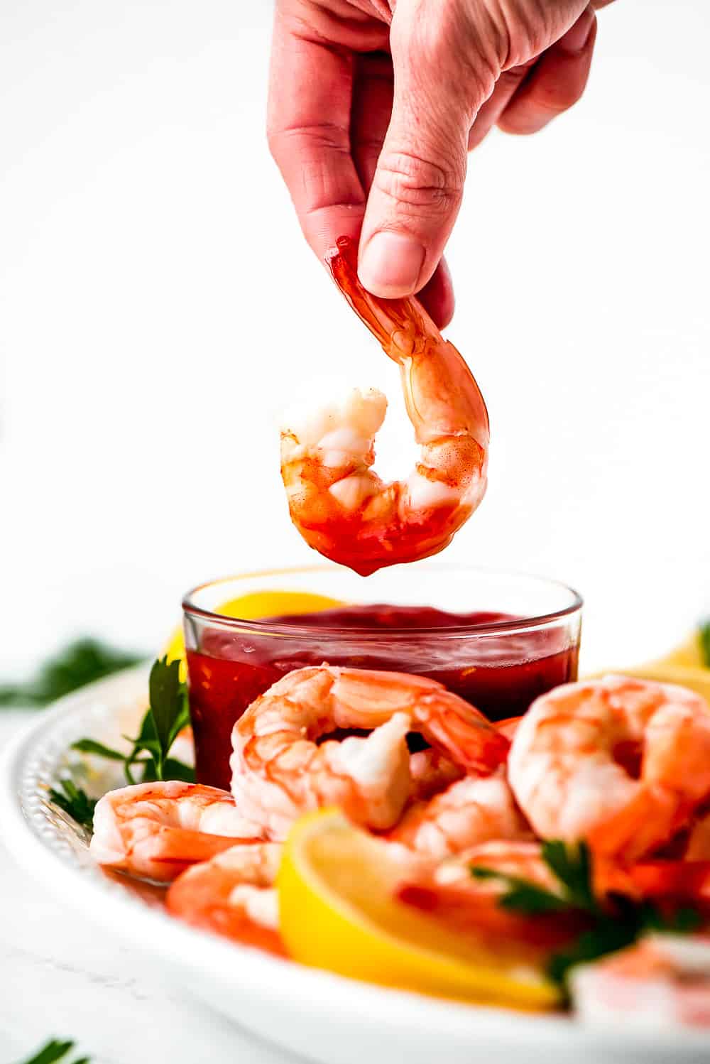 Shrimp Cocktail is a classic party appetizer that needs to be at your next gathering! This party favorite is easy to throw together and can be made in advance.ย shrimp being dipped in cocktail sauce