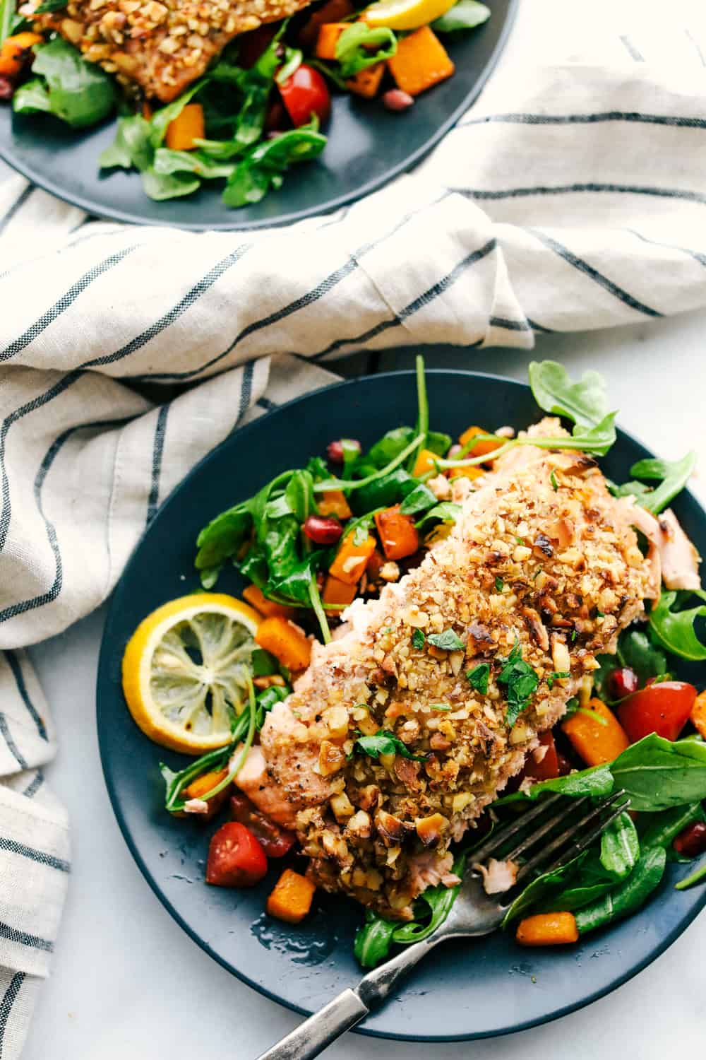 Walnut Crusted Maple Salmon is a savory salmon dish that is coated in a sweet maple syrup, delicious Dijon mustard coated with a thick walnut crust all baked to perfection. Baked in under 30 minutes! Walnut crusted maple salmon on a plate with a side salad.