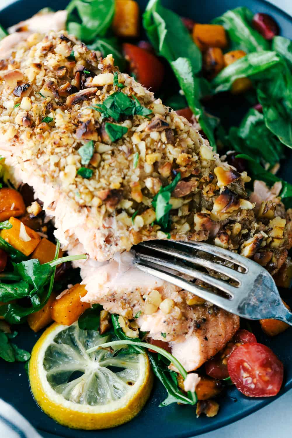 Walnut Crusted Maple Salmon is a savory salmon dish that is coated in a sweet maple syrup, delicious Dijon mustard coated with a thick walnut crust all baked to perfection. Baked in under 30 minutes! Walnut crusted maple salmon on a plate with a side salad.