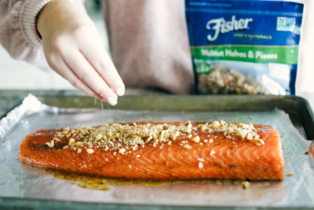 Walnut Crusted Maple Salmon is a savory salmon dish that is coated in a sweet maple syrup, delicious Dijon mustard coated with a thick walnut crust all baked to perfection. Baked in under 30 minutes! Walnut crusted maple salmon having fisher walnuts sprinkled over top.