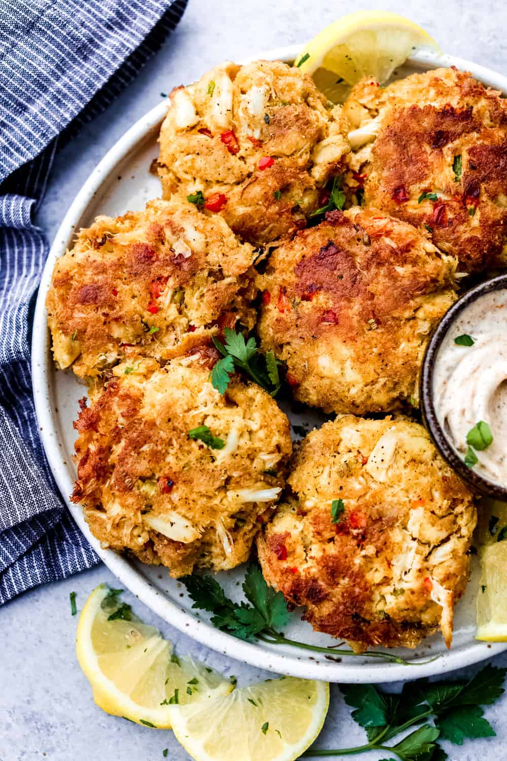 These easy-to-make crab cakes are filled with thick chunks of crab meat mixed togetherย with creamy mayonnaise and sweet red bell pepper, topped off with a kick of red pepperย flakes. The BESTย crab cake recipe you will ever use! Crab cakes on a white plate.