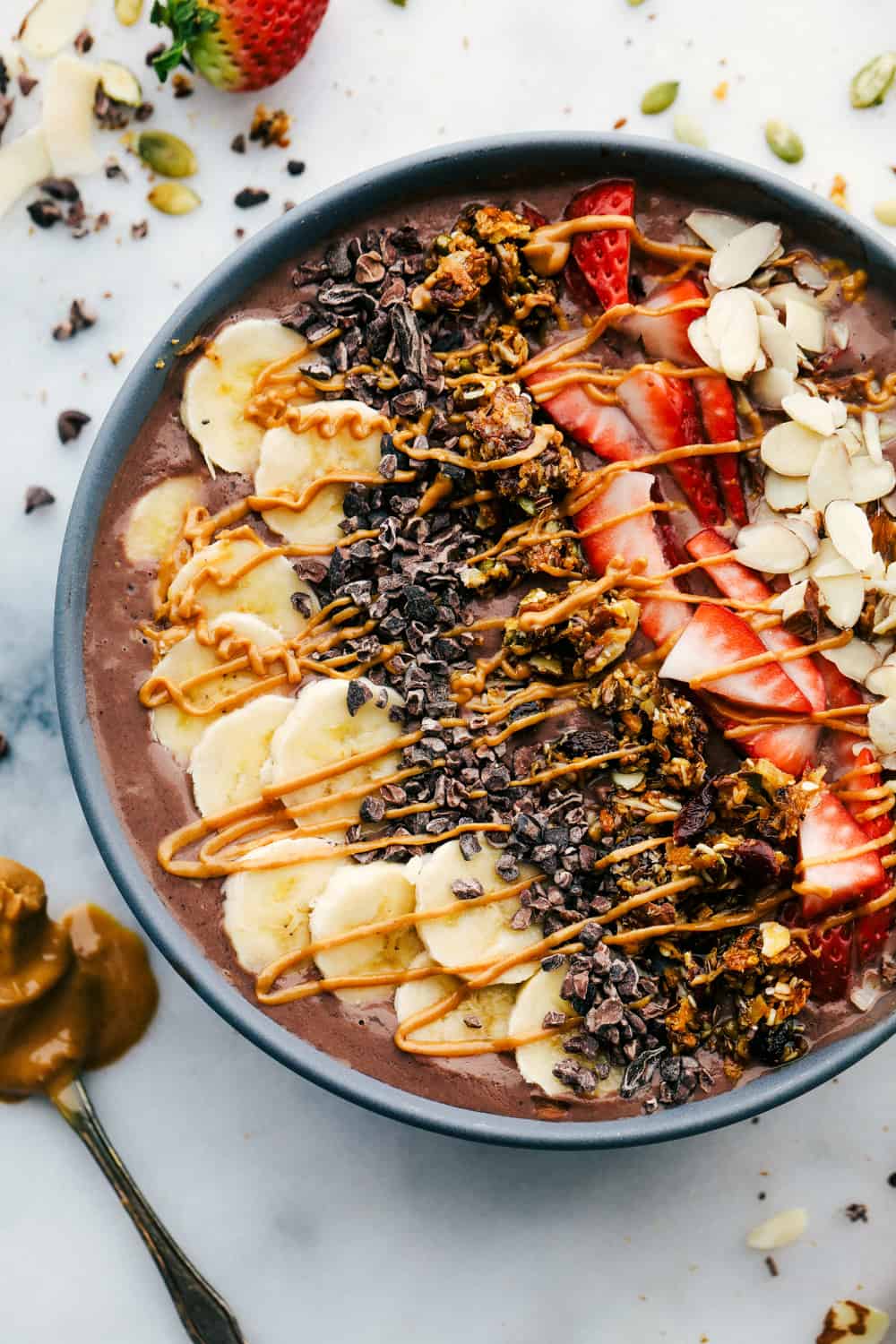 The Best Acai Bowls (Three Ways!) is a fruit filled bowl full of acai berries blended together with a juice topped with granola, fresh fruits, crunchy nuts and a variety of seeds all drizzled with a fun topping. A perfect way to start your day or keep it going! The Peanut Butter Chocolate acai bowl drizzled with peanut butter topping.