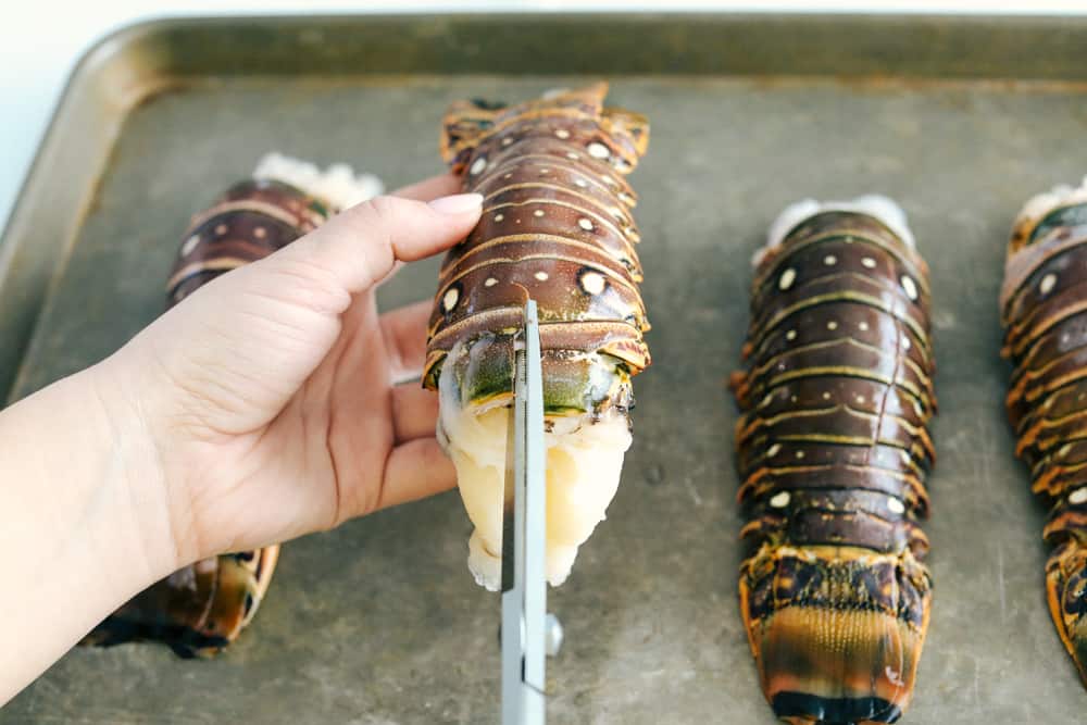The Best Lobster Tail Recipe Ever is a decadent dinner made with large lobster tails smothered with a buttery garlic herb sauce then broiled under high heat making these lobster tails tender and juicy. The ultimate indulgence! Butterflying the lobster tails down the middle of their shell.