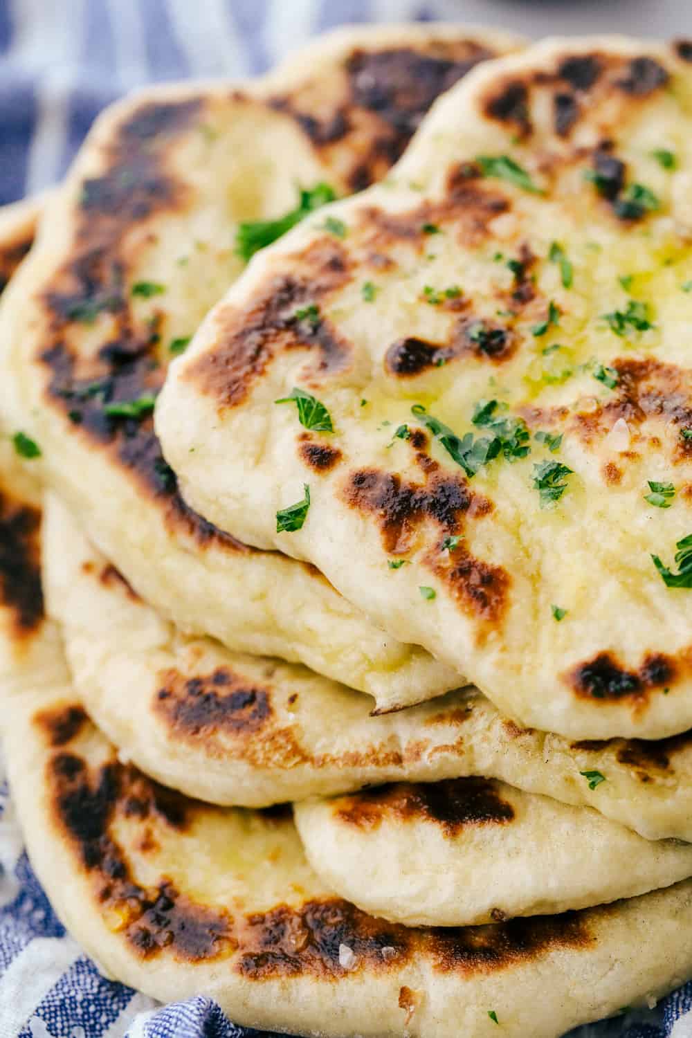 Perfect Naan Bread with Garlic Butter is a sweet and buttery flatbread with simple ingredients that is thick and rich that fluffs up and softens when cooked then brush on a garlic buttery sauce for added flavor. Learn how to make homemade naan bread! Naan bread stacked on top of each other.