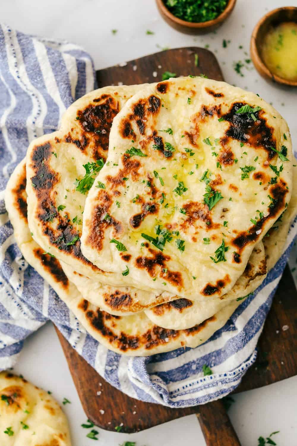 Perfect Naan Bread with Garlic Butter is a sweet and buttery flatbread with simple ingredients that is thick and rich that fluffs up and softens when cooked then brush on a garlic buttery sauce for added flavor. Learn how to make homemade naan bread! Overhead shot of naan bread stacked together.