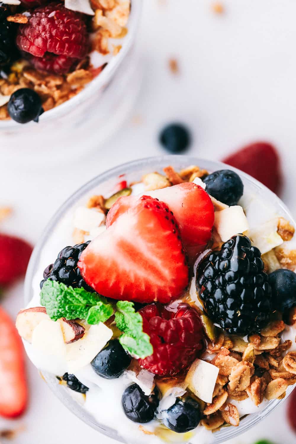 Yogurt Parfait recipe is a simple breakfast or snack that starts with a thick and creamy yogurt layered with homemade granola and fresh berries then topped with more fresh berries and a honey drizzle. A delicious breakfast ready in only a few minutes! Yogurt parfait topped with fresh strawberries, blackberries, raspberries and blueberries with granola garnished on top.