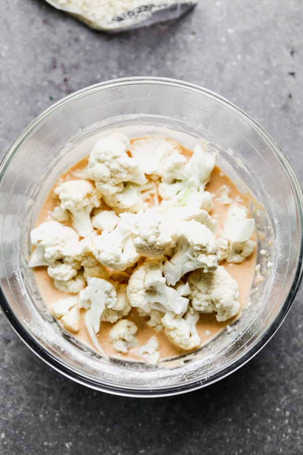 Buffalo Cauliflower takes all your favorite things about buffalo chicken wings - the crispy exterior, soft interior, and tangy, spicy buffalo taste - and turns them into a healthier option you don't have to feel guilty about eating. Super easy and so good! Cut up cauliflower in a bowl of buffalo sauce.