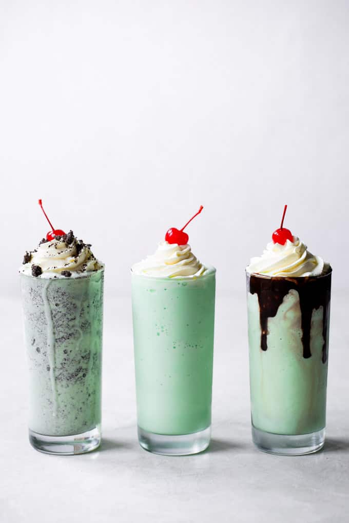 line at the drive-thru and make your own at home! Three tall glasses of shamrock milkshake with whip cream and a cherry on top of each of them.