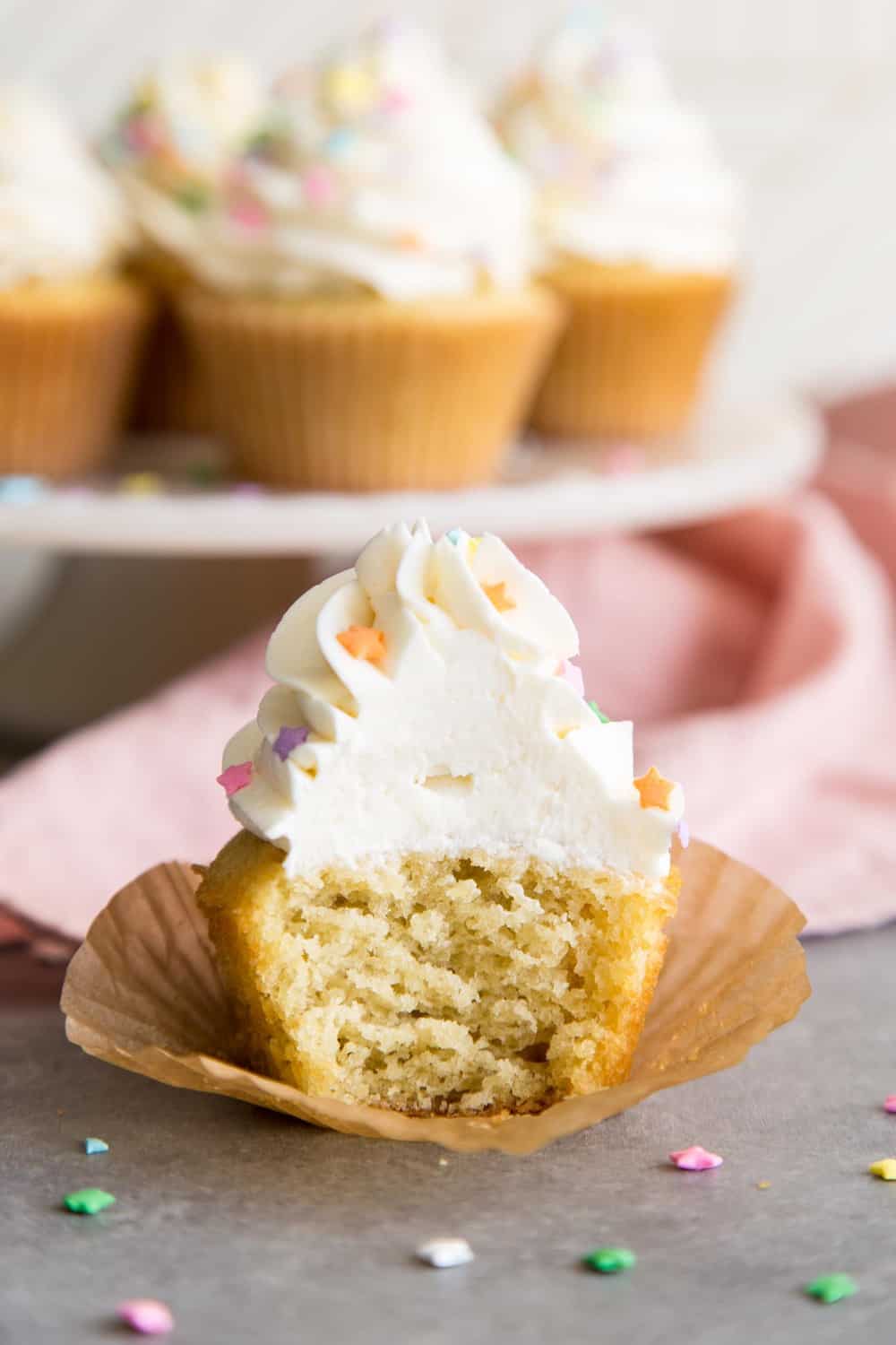 Easy Vanilla Cupcakes with vanilla frosting are such a classic treat for birthdays and perfect for any celebratory occasions. These moist cupcakes with their creamy crown of frosting will surely bring a smile to your face! A half eaten vanilla cupcake