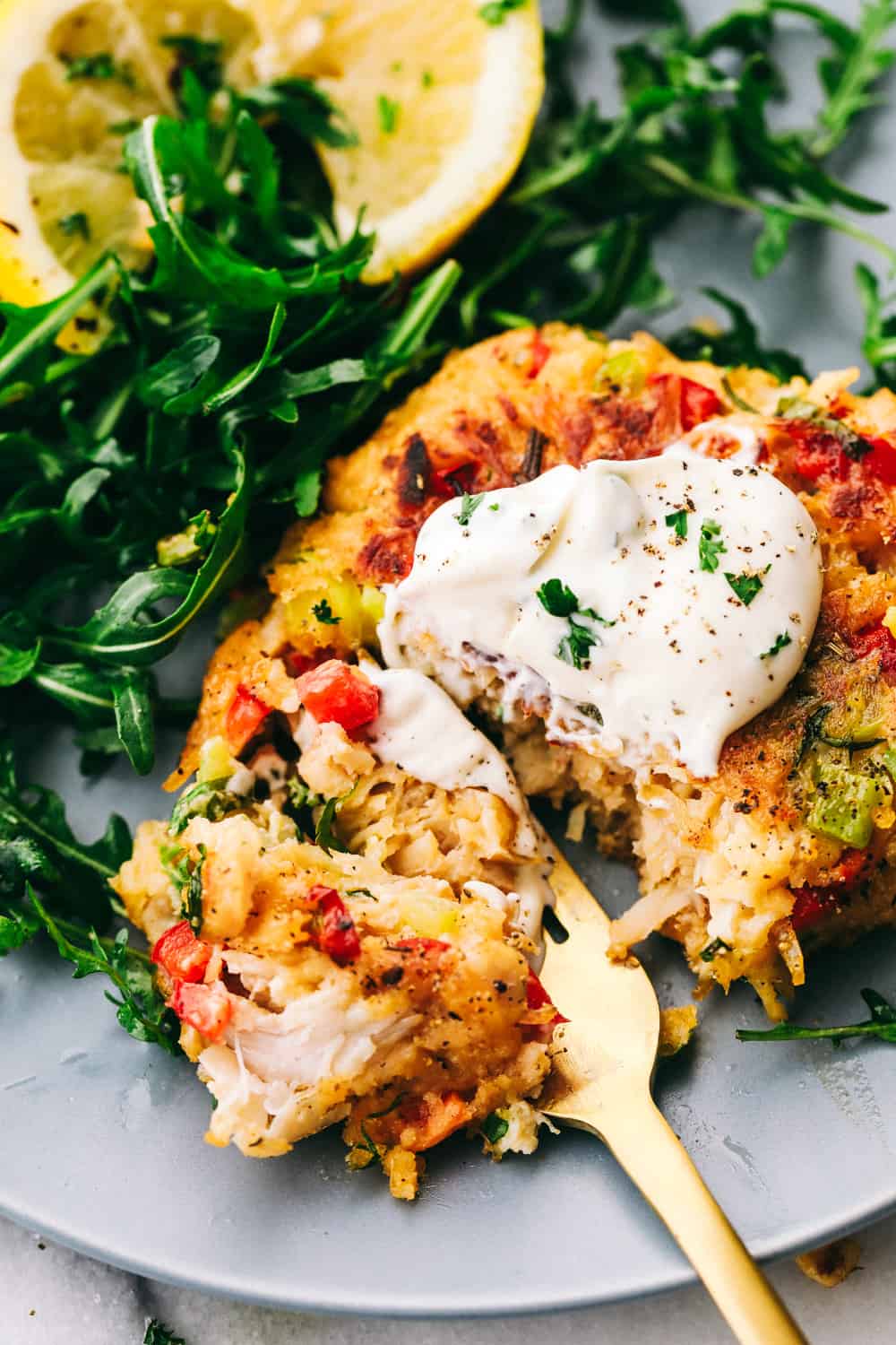 Chicken Croquettes are filled with panko, chopped redย and green bell peppers, cookedย chicken, creamy mayonnaise, seasoned with garlic powder and mixed together into small rounds. These are SO easy to make!ย Chicken croquettes cut for a bite with a gold fork, lettuce and lemon on the side.
