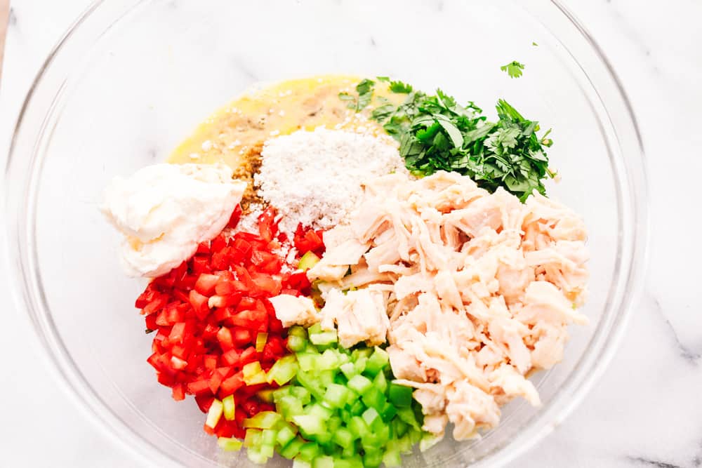 Chicken Croquettes are filled with panko, chopped redย and green bell peppers, cookedย chicken, creamy mayonnaise, seasoned with garlic powder and mixed together into small rounds. These are SO easy to make!ย Chicken, bell peppers, garlic powder, beaten egg, mayonnaise and parsley all in one glass bowl.