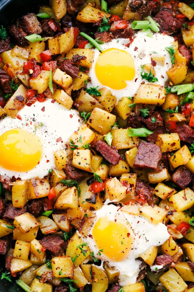 This corned beef hash breakfast is filled with chopped crispy potatoes and bell peppers with corned beef mixed together and a large sunny side up egg to complete the meal. Breakfast just got better with this hash! Corned beef with potatoes, corned beef and red bell peppers with eggs cooked on top.