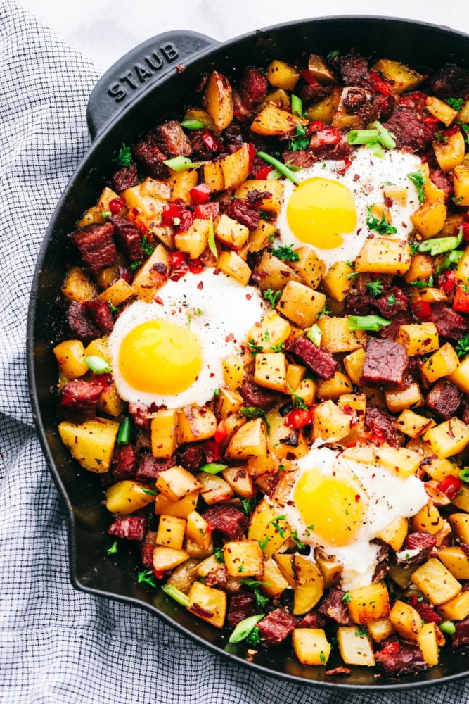 This corned beef hash breakfast is filled with chopped crispy potatoes and bell peppers with corned beef mixed together and a large sunny side up egg to complete the meal. Breakfast just got better with this hash! Corned beef in a skillet with eggs on top.