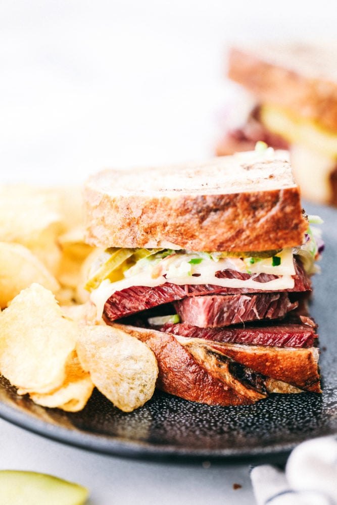 This corned beef sandwich is packed with so much flavor from the thick slices of corned beef layered with all the favorite toppings making this sandwich irresistible. Leftover corned beef for the WIN!ย Corned beef sandwich on a plate with potato chips on the side.